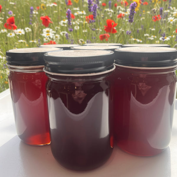 Three jars of honey on a white surface with a blurred background