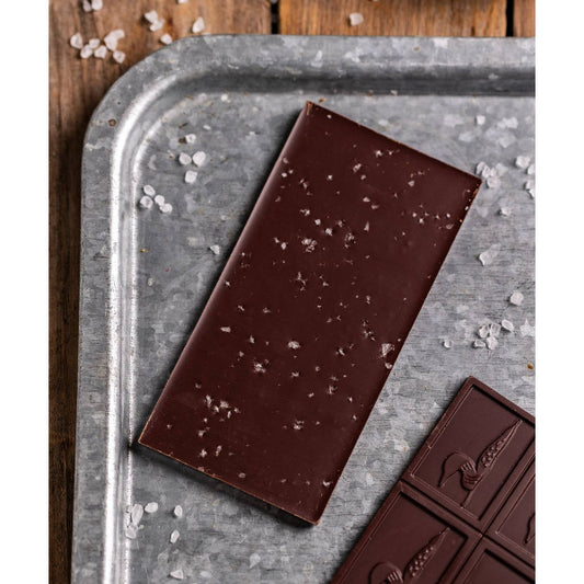 Dark chocolate bar with visible sea salt on a metal tray