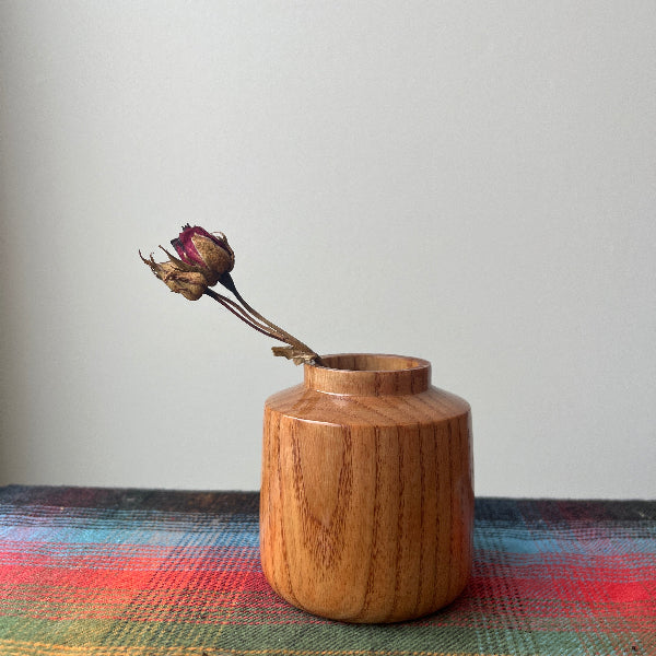 Wooden vase with dried flowers on a colorful fabric background