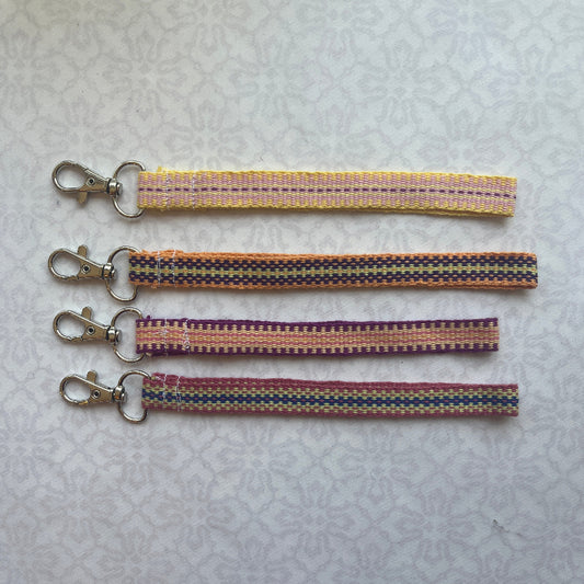 Three colorful keychain straps with metal clasps on a light gray background