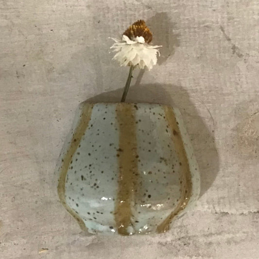 Small ceramic vase with a white flower on a textured surface