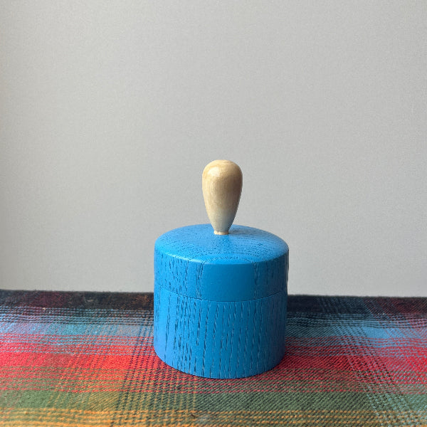 Blue cylindrical object with a wooden stick on a colorful fabric background