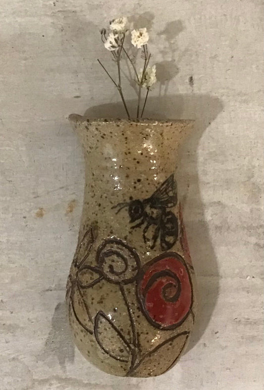 Decorative ceramic vase with a bee and floral design on a textured surface