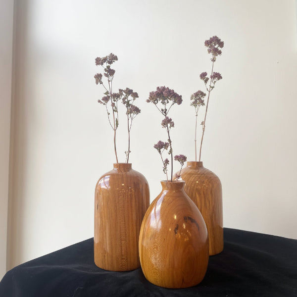 Wooden vase with dried flowers on a white wall