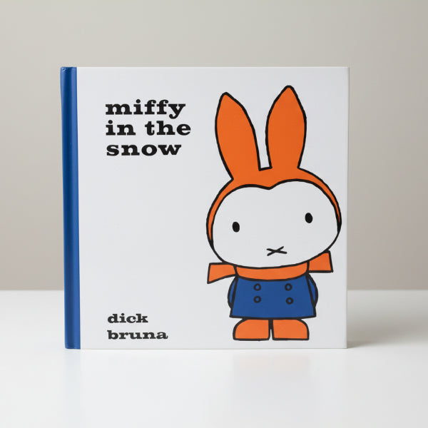 Book titled 'miffy in the snow' by Dick Bruna on a wooden surface