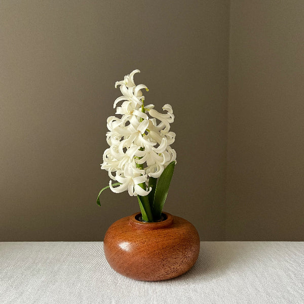 White flowers in a wooden vase on a neutral background