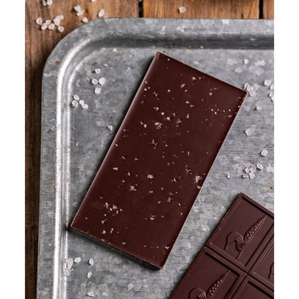 Dark chocolate bar with visible sea salt on a metal tray