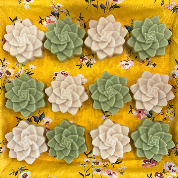 Decorative pillow with floral pattern and succulent-like fabric flowers on a wooden surface.