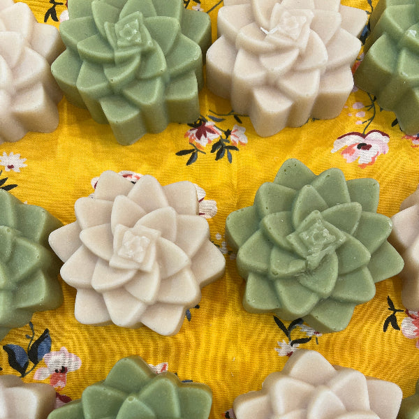 Decorative succulent-shaped soaps on a yellow floral fabric background