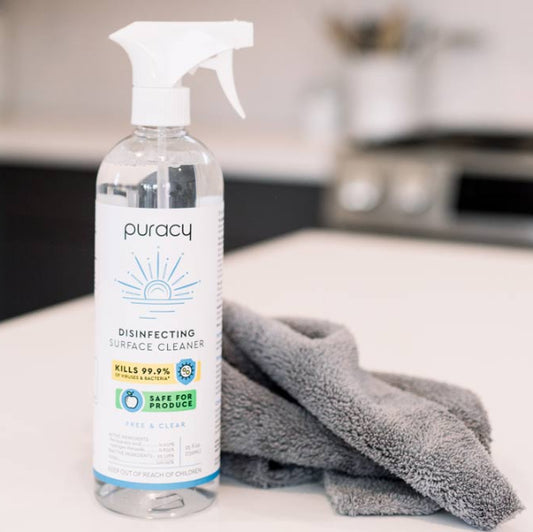 Puracy disinfecting surface cleaner bottle on a kitchen counter with a gray cloth.