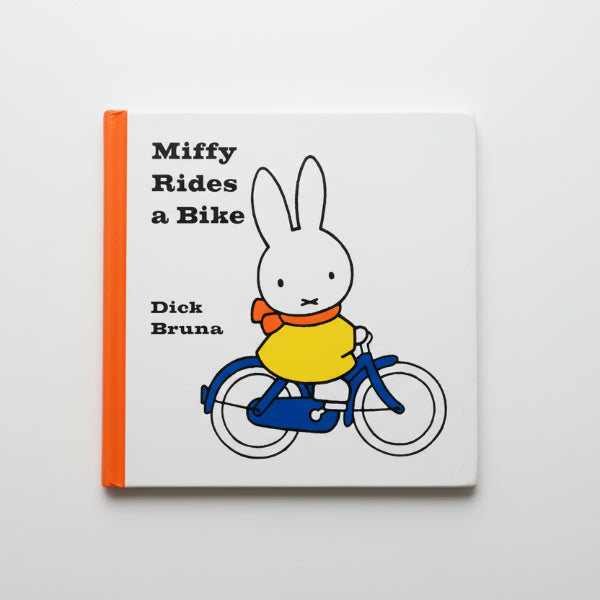 Book titled 'Miffy Rides a Bike' by Dick Bruna on a wooden surface