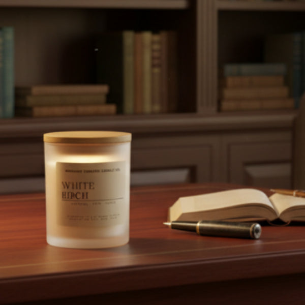 White birch candle from Midnight Embers Candle Co. on a wooden surface with a store background.